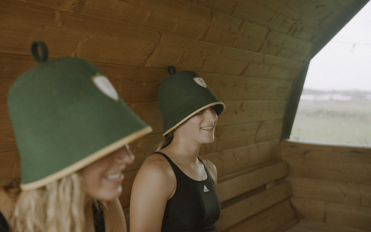 Two athletes talking in the sauna wearing Rí sauna hats, unexpected benefits of a sauna hat