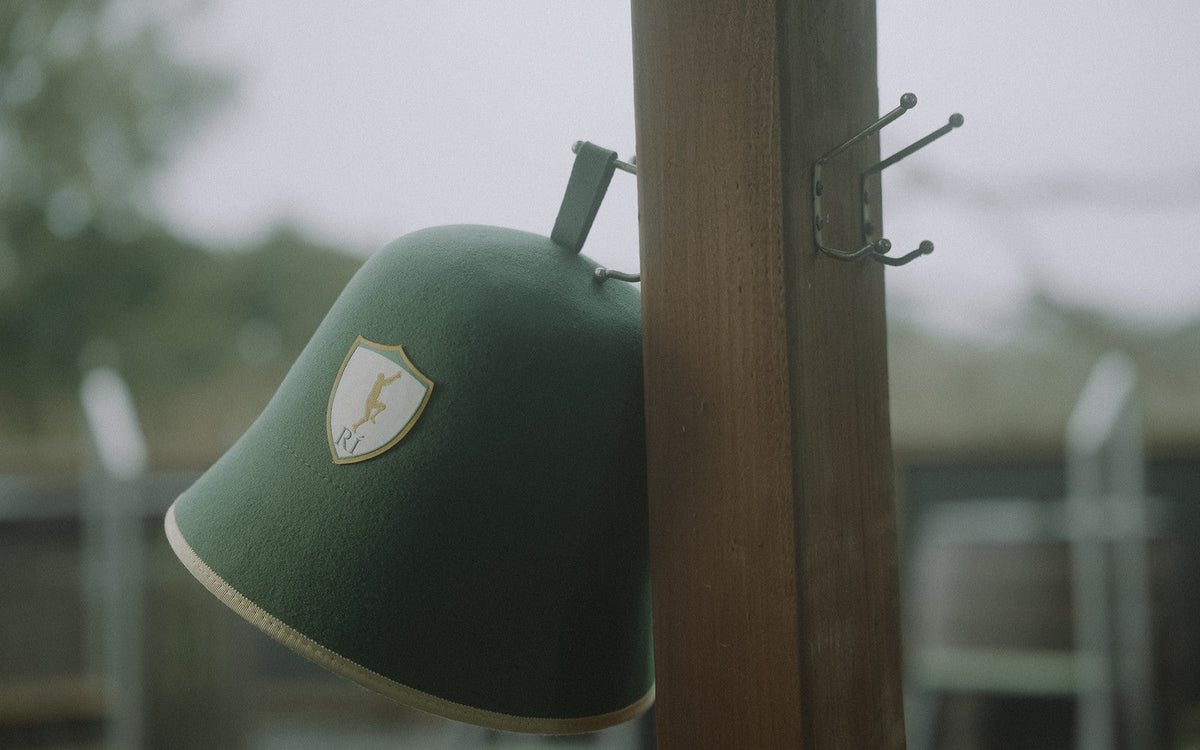 Rí sauna hat on a hook with a barrel sauna behind, wearing a sauna hat outside the spa