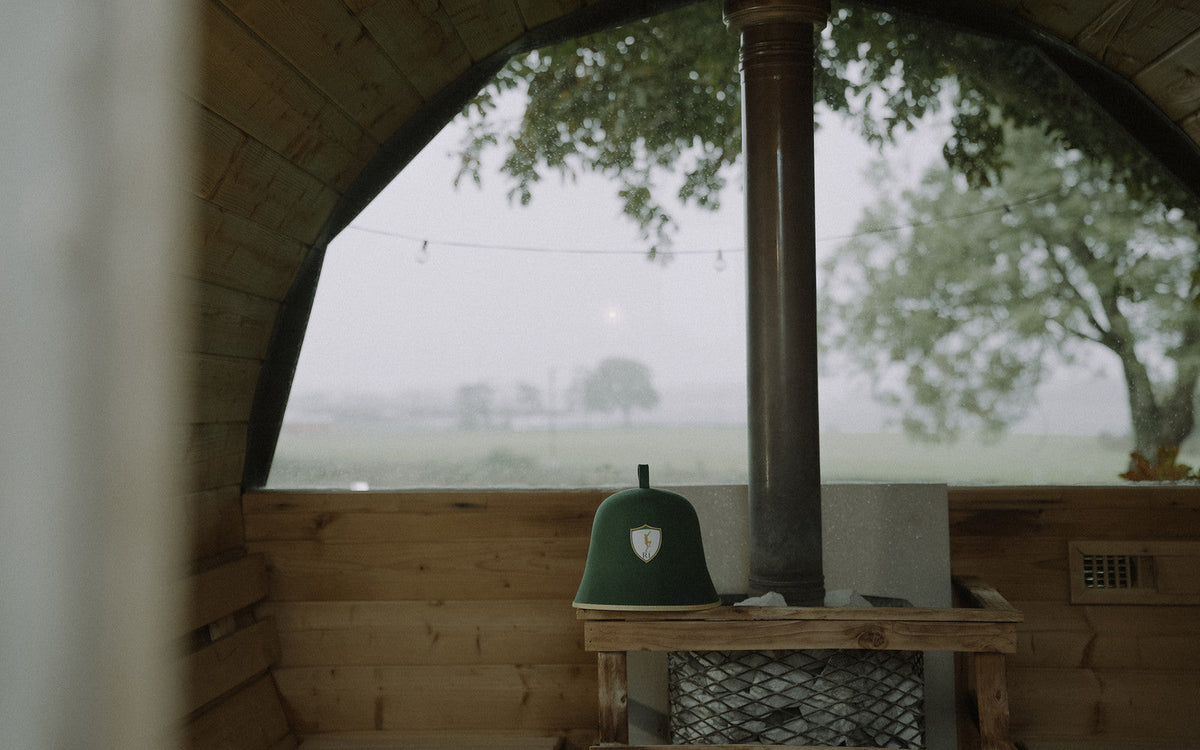 Rí sauna hat beside a wood-fired stove with the lake beyond, infrared vs traditional sauna