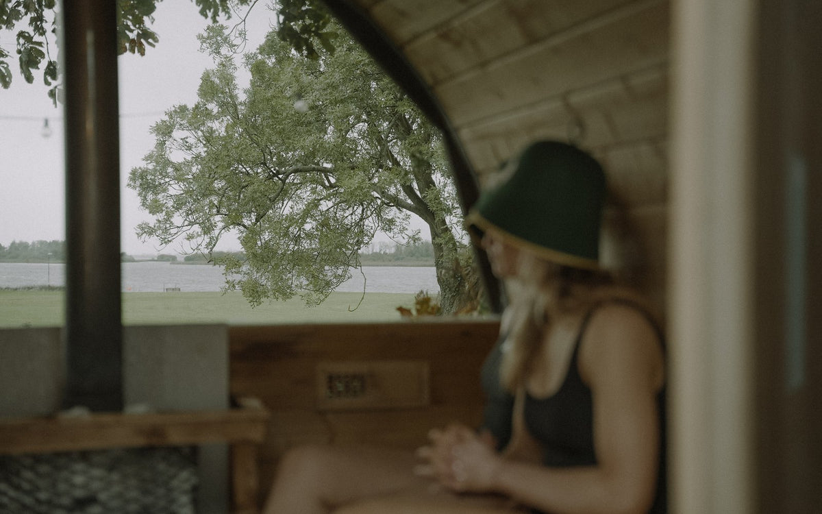Athlete in a Rí Sauna Crown inside a barrel sauna, Loch Rí visible through the window