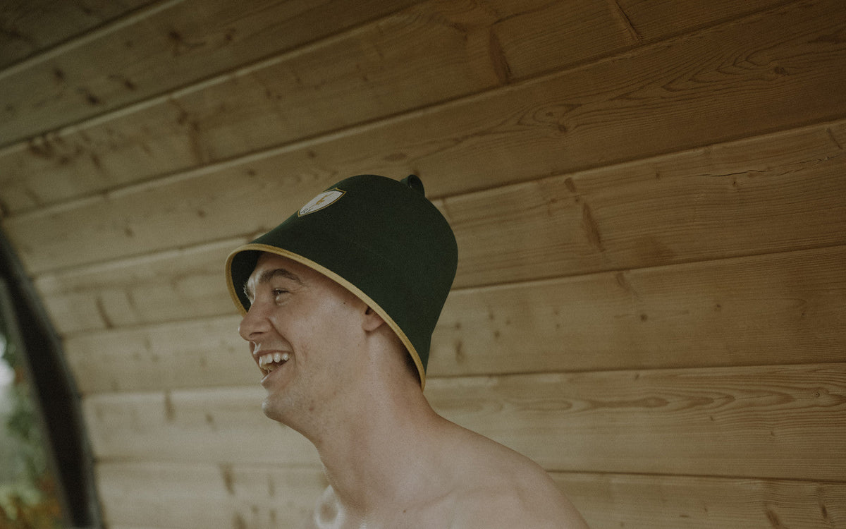 Man laughing in a barrel sauna wearing the Rí Sauna Crown, the growth hormone sauna protocol