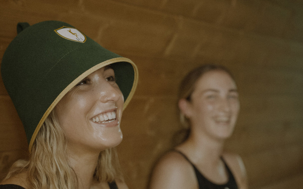 Athlete laughing in the sauna wearing the Rí Sauna Crown, why you need a sauna hat to stay in longer